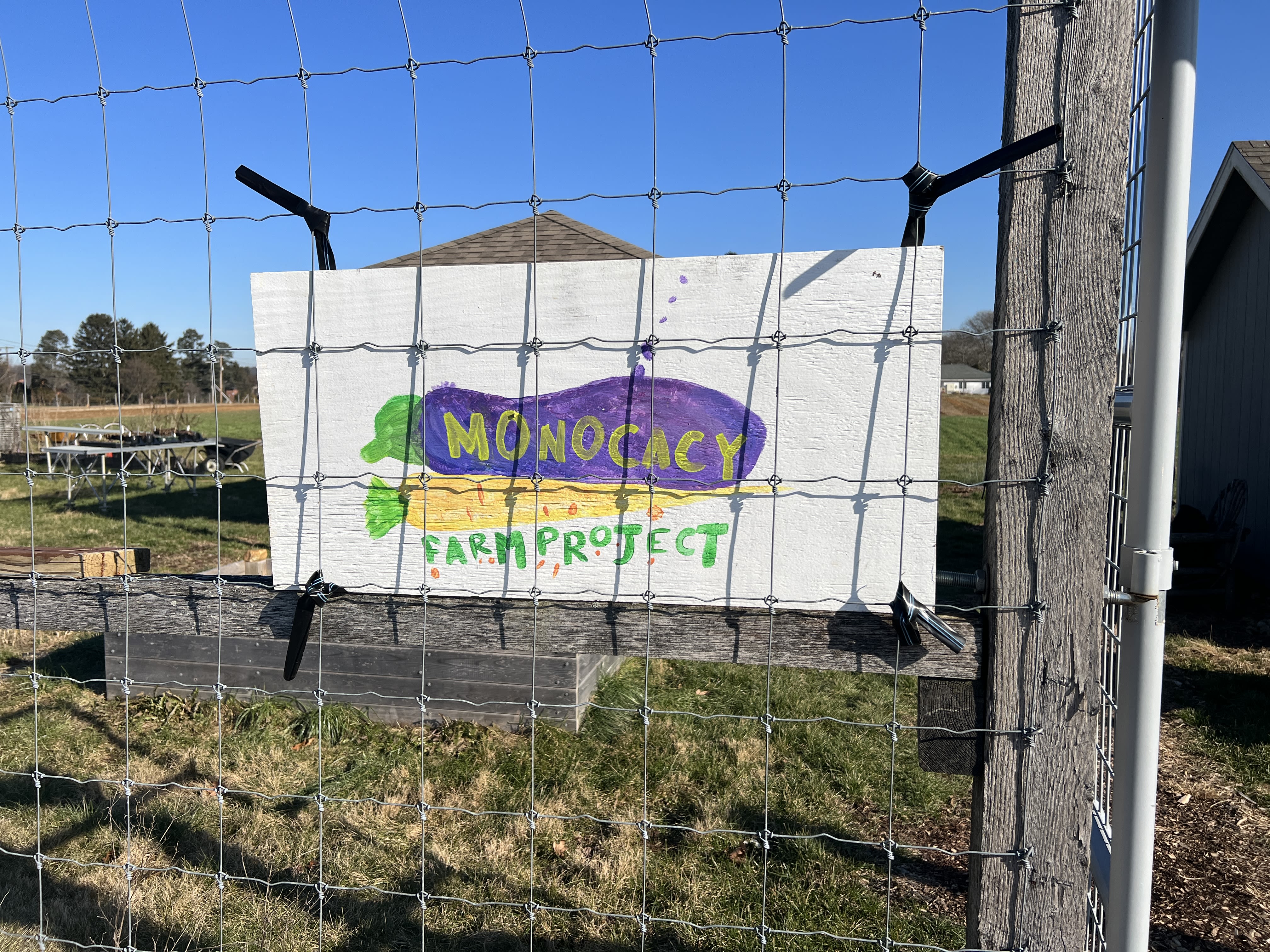 A hand-painted sign that reads "Monocacy Farm Project" over a cartoon eggplant and carrot.